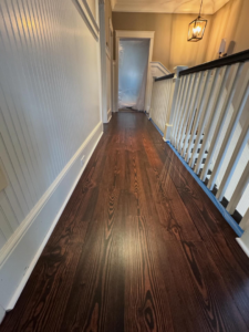 Hardwood floor staining in progress in a hallway by Trades by Taylor LLC, ensuring a clean job in Huntsville, AL.