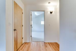 Newly installed hardwood flooring and a modern wall sconce light fixture in a hallway by Matt Bennett Construction in Junction City, OR