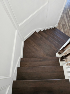 Newly installed hardwood staircase with elegant wainscoting on the walls by Amazing Spaces 21 in Orlando, FL