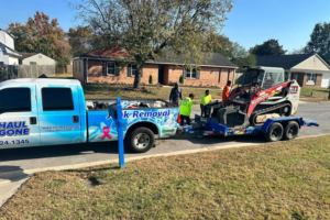 A Haul Gone 757 junk removal truck with a skid steer loader on a trailer, indicating heavy-duty junk removal capabilities in Chesapeake, VA.