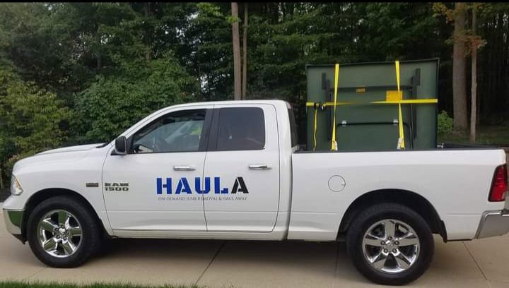 A HAULA Junk Removal truck transporting a large green item securely strapped in its bed, demonstrating efficient removal in Canton, OH.