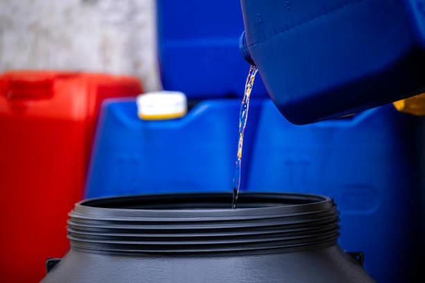 Transferring hazardous liquid from a blue container into a drum by Environmental & Hazmat Services in Ashford, AL.
