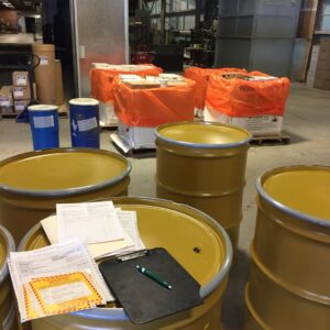 Hazardous waste barrels and bags with accompanying paperwork, managed by MLi Environmental in South Portland, ME.