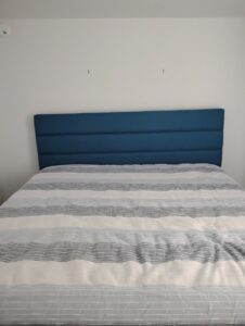 A blue upholstered headboard installed on a white wall, a furniture assembly service provided by McCollister Contracting LLC in New Castle, DE.