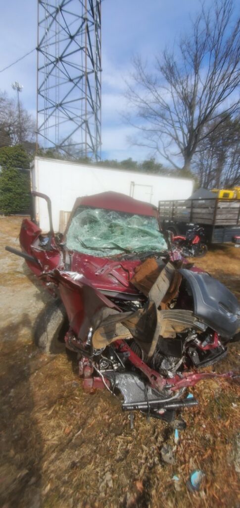 A heavily damaged red SUV, seen from the front, ready for automotive removal by Don's Automotive Removal in Thomasville, NC.