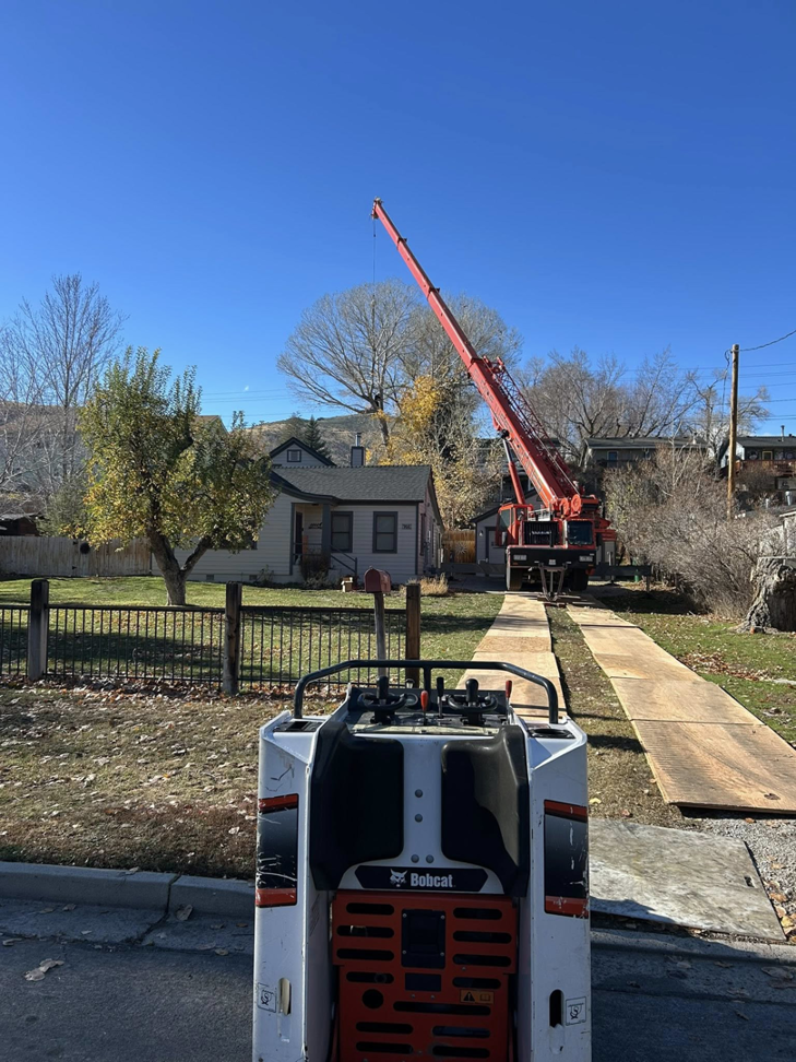 Heavy equipment, including a crane and Bobcat loader, with ground protection for tree removal by Capital Tree Care LLC in Carson City, NV.