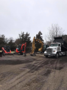 Heavy equipment including excavators and a dump truck used by Us General, Inc. in Brockton, MA.