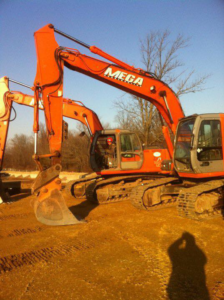 Two large orange excavators with Mega branding on a construction site by Mega Construction in Philadelphia, PA.