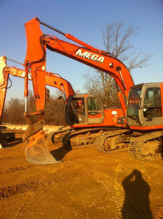 Two large orange excavators with Mega branding on a construction site by Mega Construction in Philadelphia, PA.
