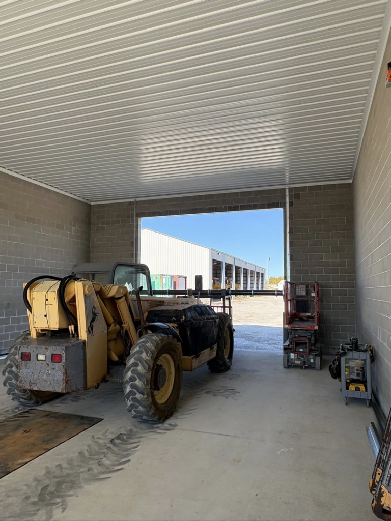 Heavy equipment inside a commercial building with an open garage door, representing contracting work by Gateway Door and Contracting in House Springs, MO.