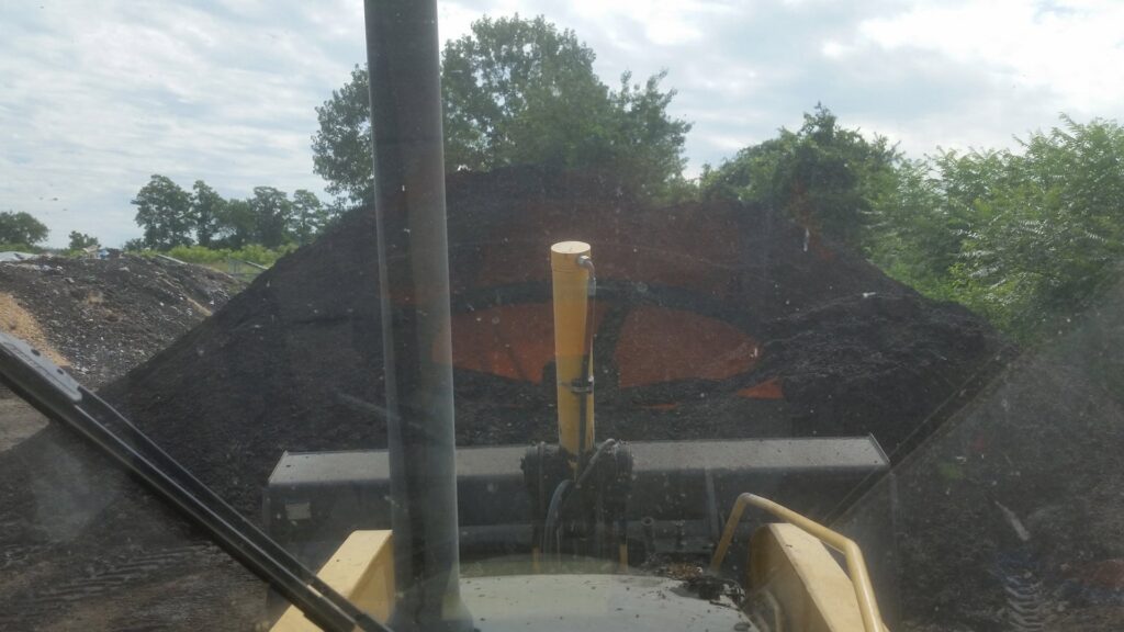 Heavy equipment moving a large pile of compost or organic waste at Windham Solid Waste Management District in Brattleboro, VT.