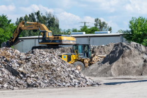 Heavy equipment, including an excavator and loader, moving large piles of debris at Global Recycling of Tampa Bay in Tampa, FL.