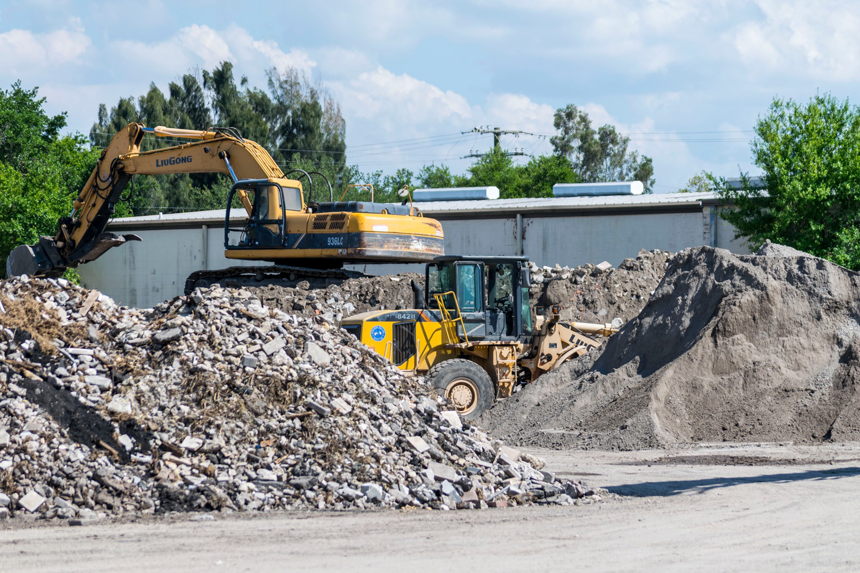 Heavy equipment, including an excavator and loader, moving large piles of debris at Global Recycling of Tampa Bay in Tampa, FL.