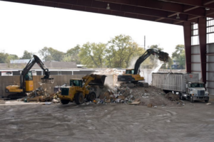 Heavy equipment processing large piles of junk and waste at the Carolina Waste facility in Charleston, SC.