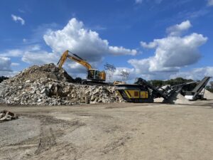 Heavy equipment processing large piles of concrete and rubble for disposal by Expert Dumpster in Rochester, NY.