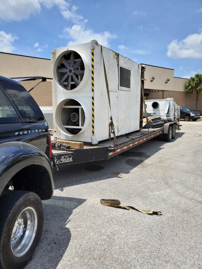 Large industrial HVAC unit being transported on a flatbed trailer by Jugganott Recycling, LLC in Orlando, FL.