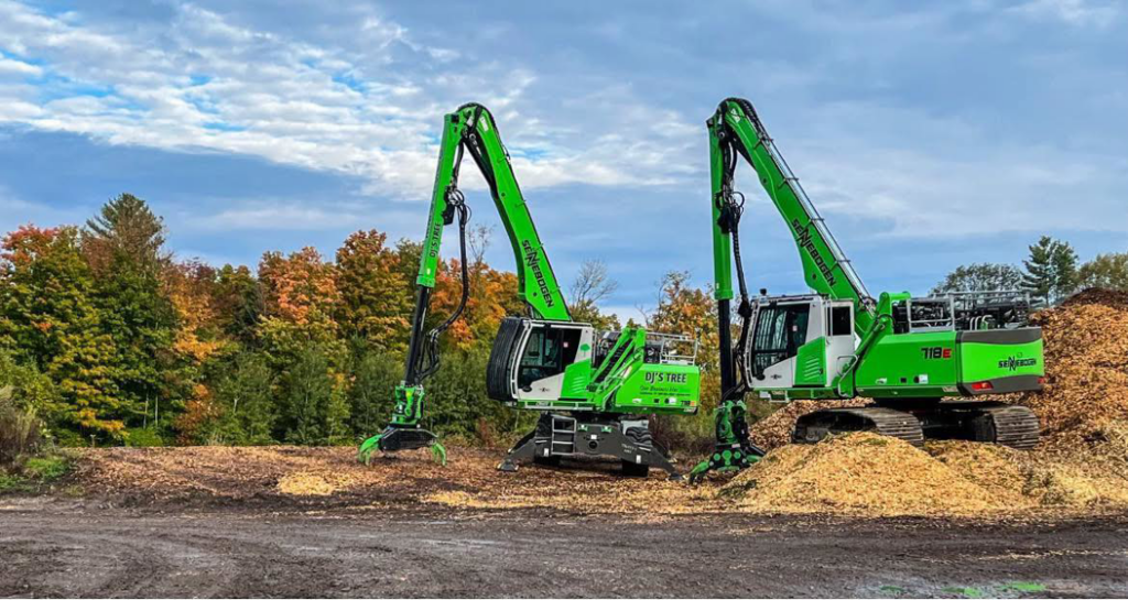 Two green heavy equipment machines, likely wood chippers, next to piles of wood chips for DJ's Tree Service in Colchester, VT.