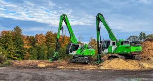 Two green heavy equipment machines, likely wood chippers, next to piles of wood chips for DJ's Tree Service in Colchester, VT.