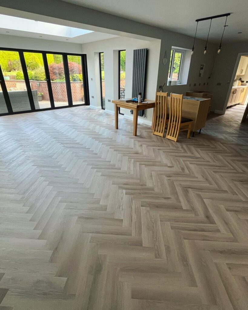 Elegant herringbone pattern wood-look flooring installed in a modern room by MDN Roofing 2 Flooring LLC in Fort Worth, TX.