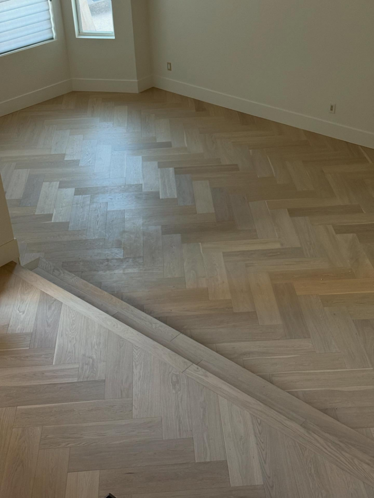 Herringbone pattern hardwood floor showing a clean transition, expertly installed by Arizona Prestige Flooring in Surprise, AZ