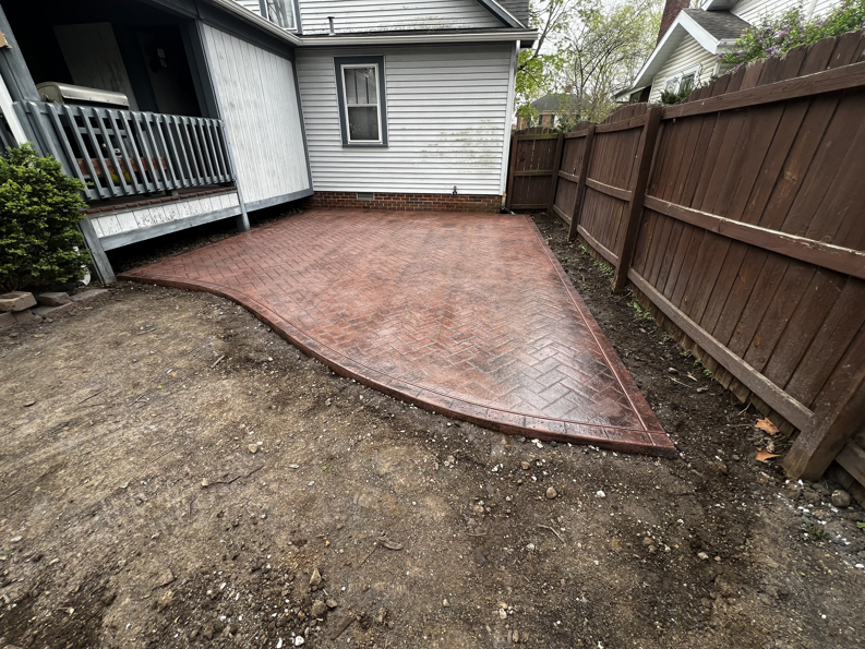 A newly installed herringbone stamped concrete patio next to a house by Lafayette Concrete & Remodel, LLC in Lafayette, IN