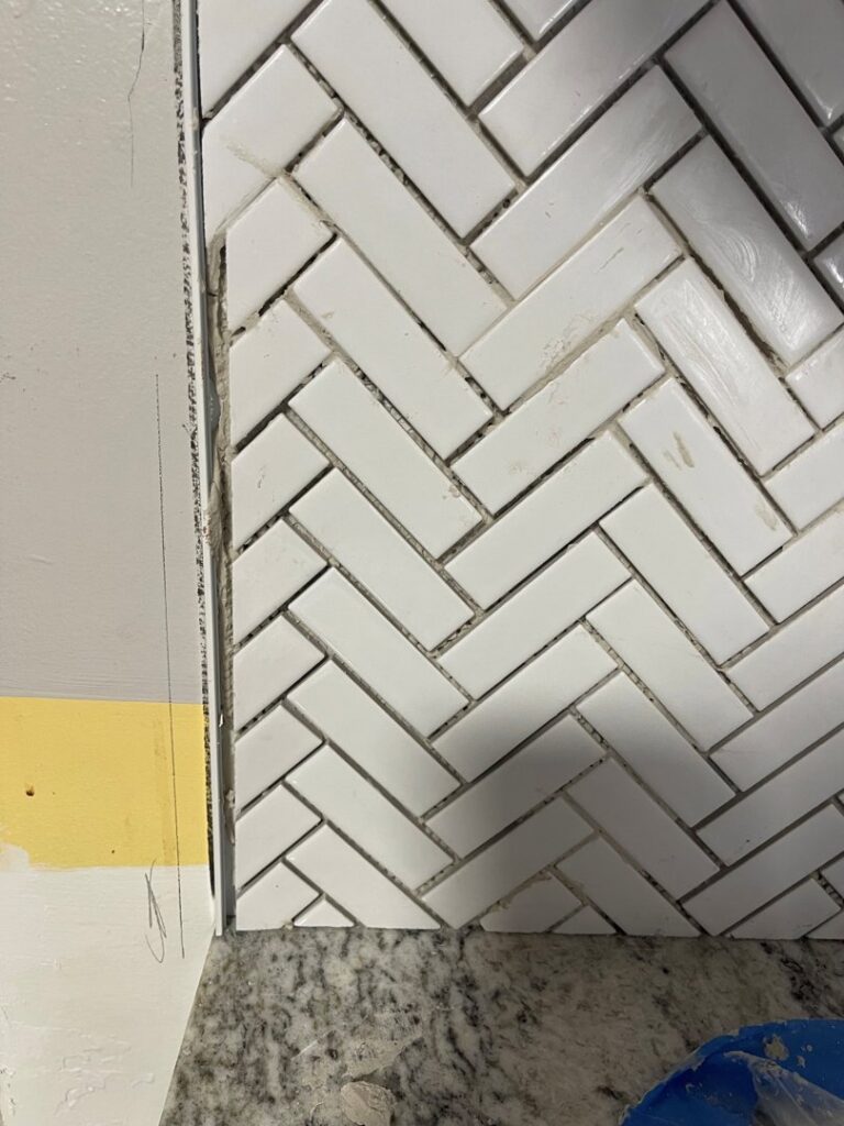 Close-up of white herringbone tile backsplash being installed above a countertop by Men Construction in Lowell, MA.