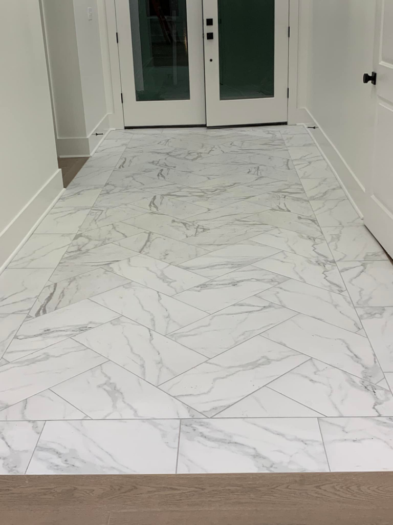 Newly installed herringbone pattern tile flooring in a hallway by Baudoin Custom Homes in Lafayette, LA.