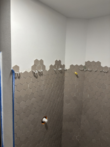 Close-up of hexagonal wall tiles being installed in a bathroom by Kaufman Construction in West Des Moines, IA.