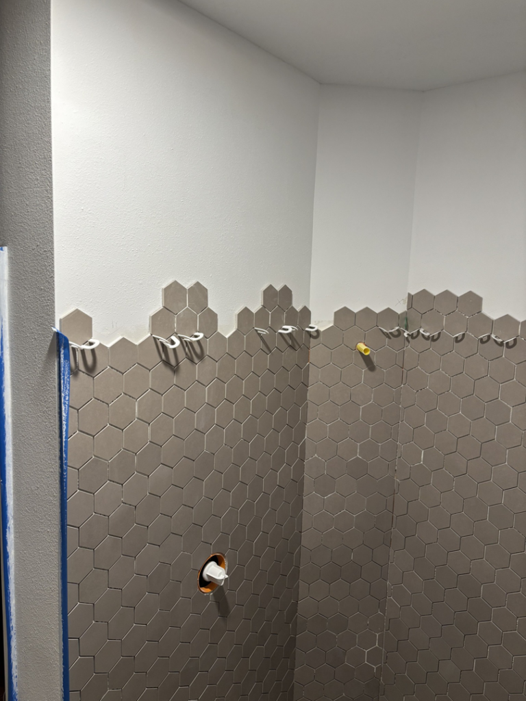 Close-up of hexagonal wall tiles being installed in a bathroom by Kaufman Construction in West Des Moines, IA.