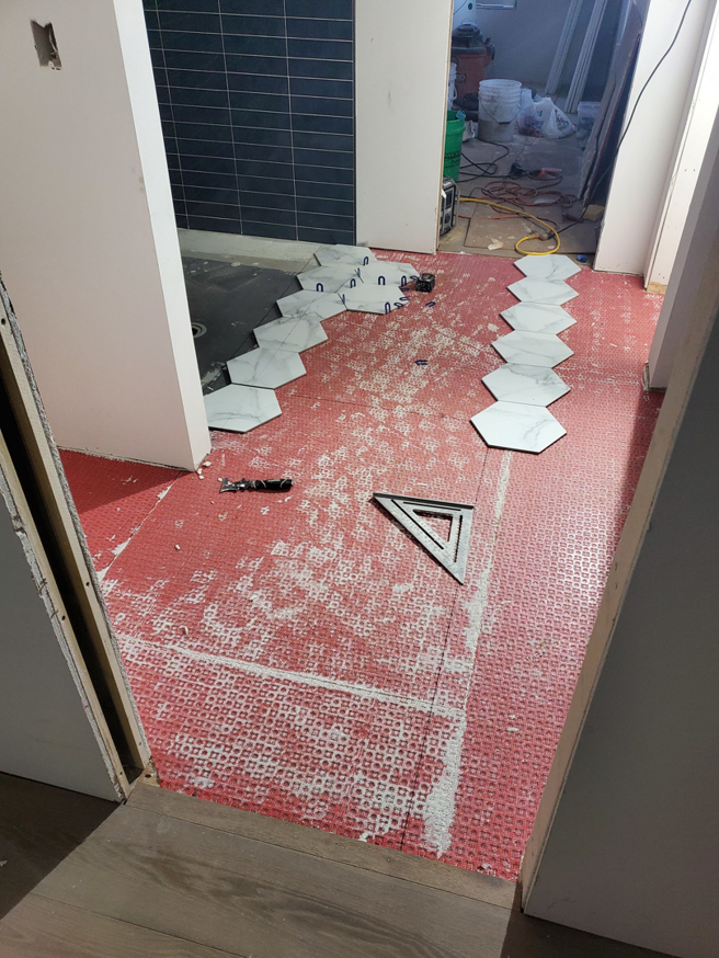 Hexagonal floor tile installation in progress in a hallway by Tile Works inc in Naperville, IL.