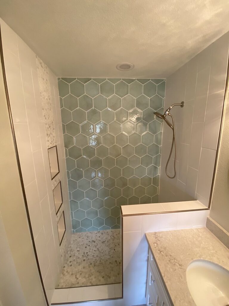 A newly installed shower with light green hexagonal tiles and white side tiles by AZ New Bath in Glendale, AZ