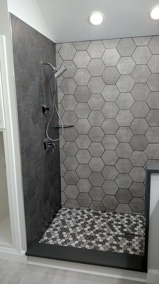 Walk-in shower featuring dark grey hexagonal wall and floor tiles by Coastal Contracting Services Inc., Virginia Beach, VA.