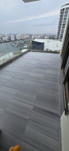 A high-rise balcony with modern grey tiled floors and a glass railing, installed by Cornerstone Services Management in Miami, FL.