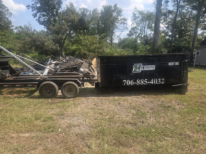 A Hinkins Disposal llc roll-off dumpster filled with construction debris and general junk, ready for removal in Augusta, GA.