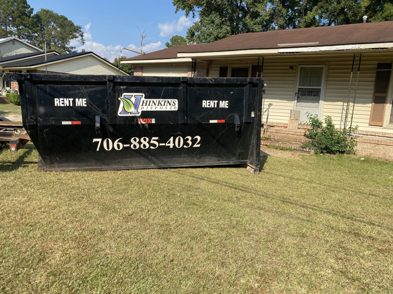 A Hinkins Disposal llc roll-off dumpster placed in a residential yard for general junk removal in Augusta, GA.
