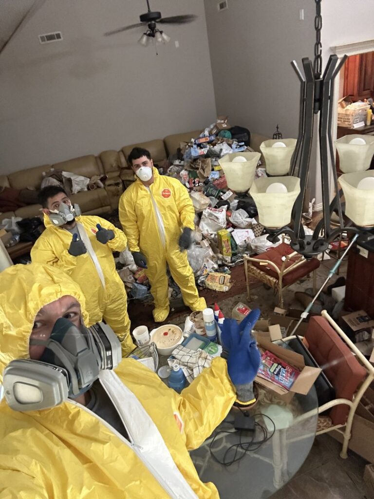 Strong Lion Junk Removal crew in protective suits preparing for a hoarder house cleanout in Fayetteville, AR.