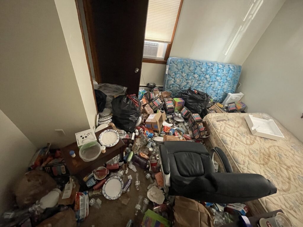 A room completely filled with trash, boxes, and old furniture, indicating a major cleanout job for Rizzo Junk Removal in Nashua, NH.