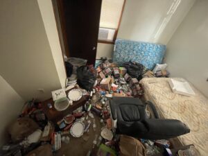 A room completely filled with trash, boxes, and old furniture, indicating a major cleanout job for Rizzo Junk Removal in Nashua, NH.