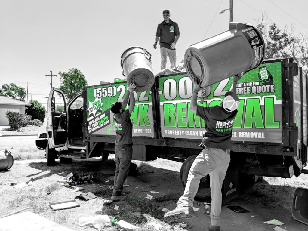 A severely cluttered and dirty kitchen undergoing cleanup by a worker in a hazmat suit from Haul-R-Us Junk Removal LLC in Fresno, CA.