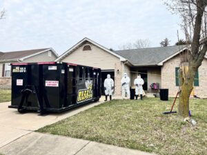 Buzz Dumpster & Junk Removal team with a dumpster at a property undergoing a cleanout service in Troy, MO.