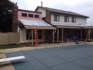 A home addition or covered patio under construction next to a swimming pool, managed by Prescott Roofing and Masonry in Carnegie, PA.