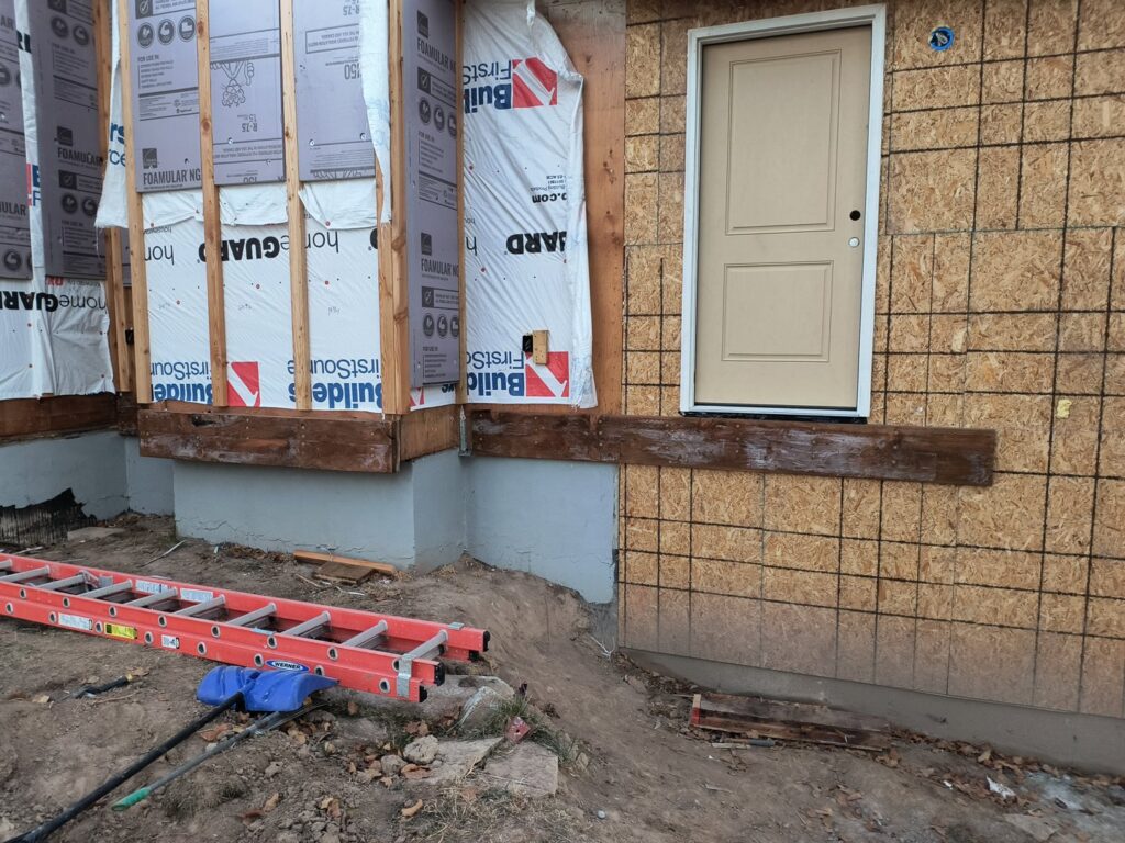 Exterior view of a home addition under construction, with a ladder and building materials, by T&K Services in Idaho Falls, ID