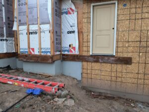 Exterior view of a home addition under construction, with a ladder and building materials, by T&K Services in Idaho Falls, ID