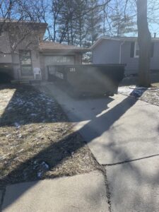 A Tags Dumpsters roll-off container placed in a residential driveway for a home cleanout service in Omaha, NE.