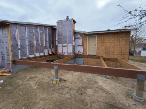 Exterior of a house undergoing renovation, with new insulation and deck framing by T&K Services in Idaho Falls, ID