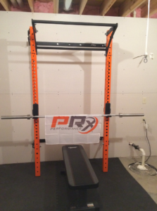 A home gym weight rack and bench installed in a basement by The Hot Handyman in Lawrence, KS.