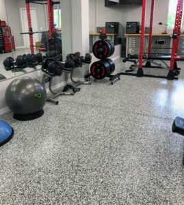 A home gym with a durable grey flake epoxy floor installed by Floor Coating Specialist in St. Petersburg, FL.