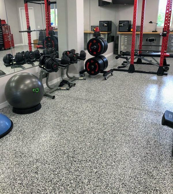 A home gym with a durable grey flake epoxy floor installed by Floor Coating Specialist in St. Petersburg, FL.