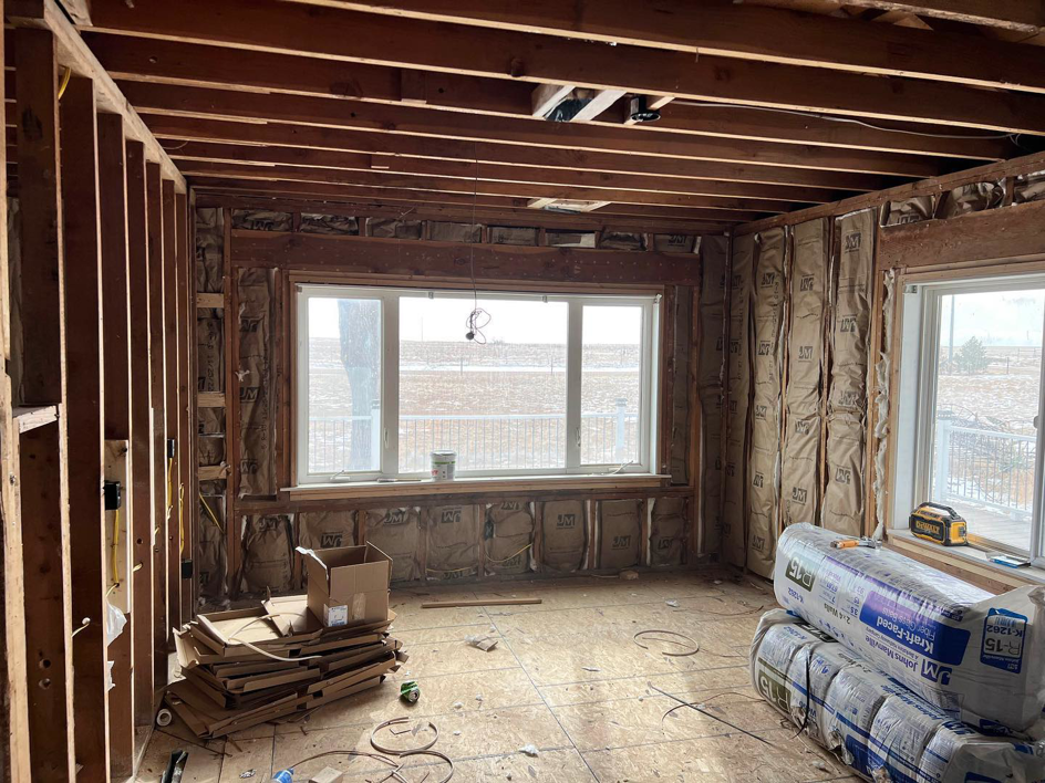 A home renovation project showing wall insulation, exposed studs, and ceiling joists by Kliesen Construction Company in Pueblo, CO.