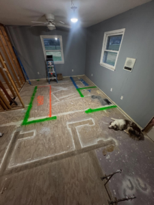 A wide shot of a home renovation project showing floor markings for layout planning and exposed studs by Shackelford Home Designs in Loveland, OH.